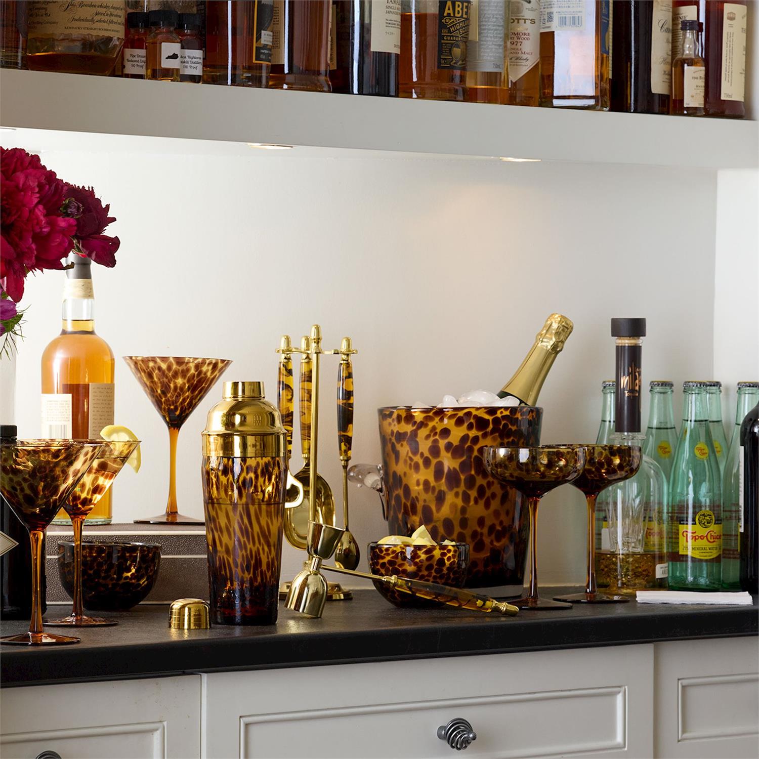 Tortoiseshell patterned barware set including cocktail shaker ice bucket and glasses on a home bar counter