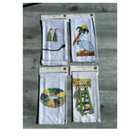 Four Mardi Gras tea towels with tassels, a pelican, king cake and a ladder