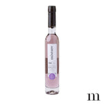 Product photograph by Mixture of a slender glass bottle of Lauren's Lavender Garden bubble bath featuring pale purple liquid, a black wax-dipped cap, and a minimalist white label with a purple circular emblem against a white backdrop