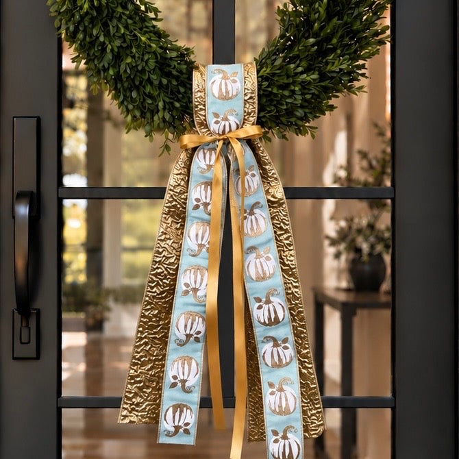 Sash of crinkled gold and aqua pumpkin-print ribbons tied with gold satin on a boxwood wreath