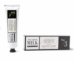 Studio product photography of Archipelago Botanicals Milk Soy Crème No/3 featuring a white squeeze tube with a black octagonal cap and its matching box against a white background with delicate floral line art and a yellow numeral three