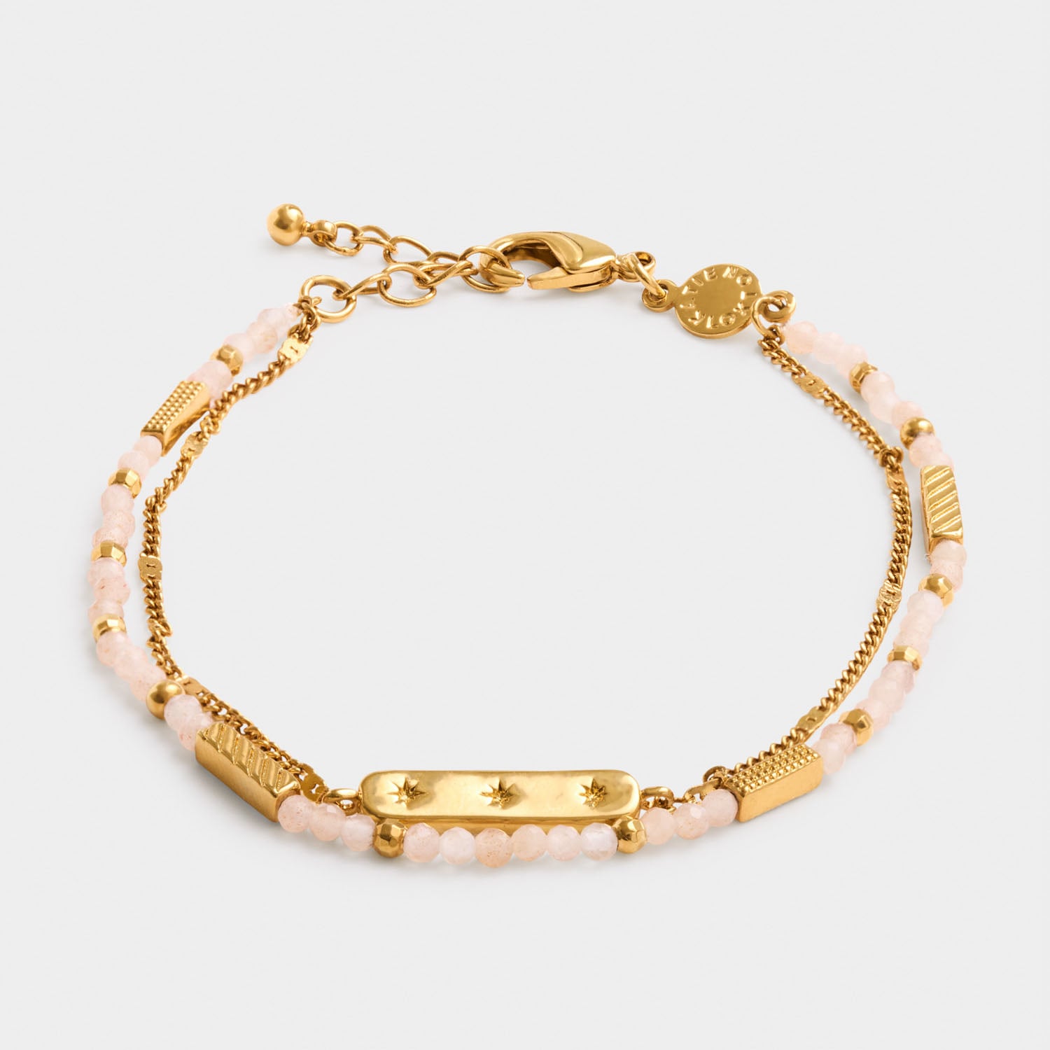 Gold chain bracelet with pink beaded accents and a central bar charm featuring star engravings