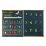A cocktail drink mixer advent calendar shown open, featuring a dark teal left panel with gold text, cocktail illustrations, and 12 numbered compartments, and a matching dark teal right panel with gold numbers 1 through 12.