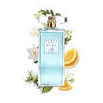 A bottle of Classica Donna perfume by Acqua di Elba, surrounded by floral arrangements and citrus fruit.