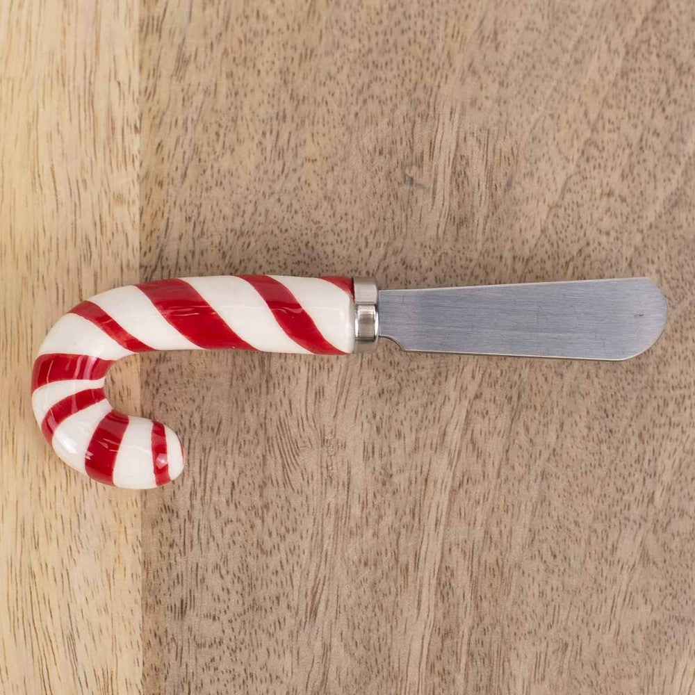 Spreader with a candy cane shaped handle on a wooden surface