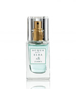 A bottle of Classica Donna perfume by Acqua di Elba, surrounded by floral arrangements and citrus fruit.
