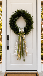 White front door with a boxwood wreath and a silver-white, gold and green ribbon sash