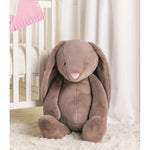 Brown plush bunny toy in a crib with white curtains and pink blanket