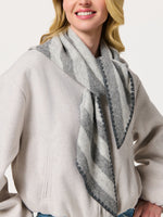 Woman wearing a gray striped triangle scarf draped open