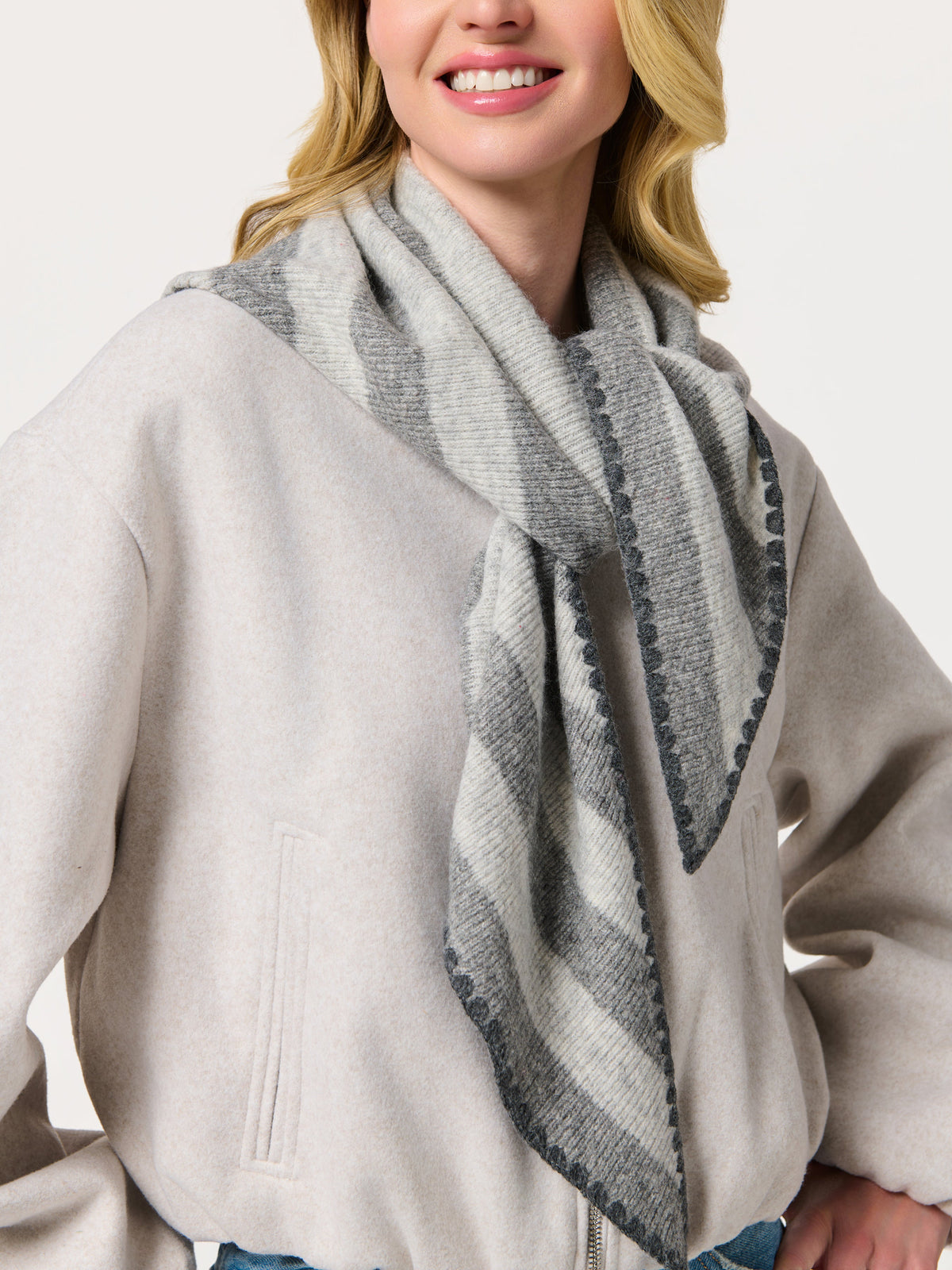 Woman wearing a gray striped triangle scarf draped open
