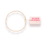 Gold beaded headband with a pink label on a white background