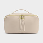 Beige toiletry bag with a gold zipper on a light gray background