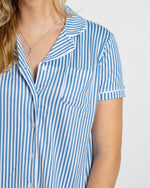 Person wearing a blue and white vertical striped short sleeve button down pajama top with a chest pocket