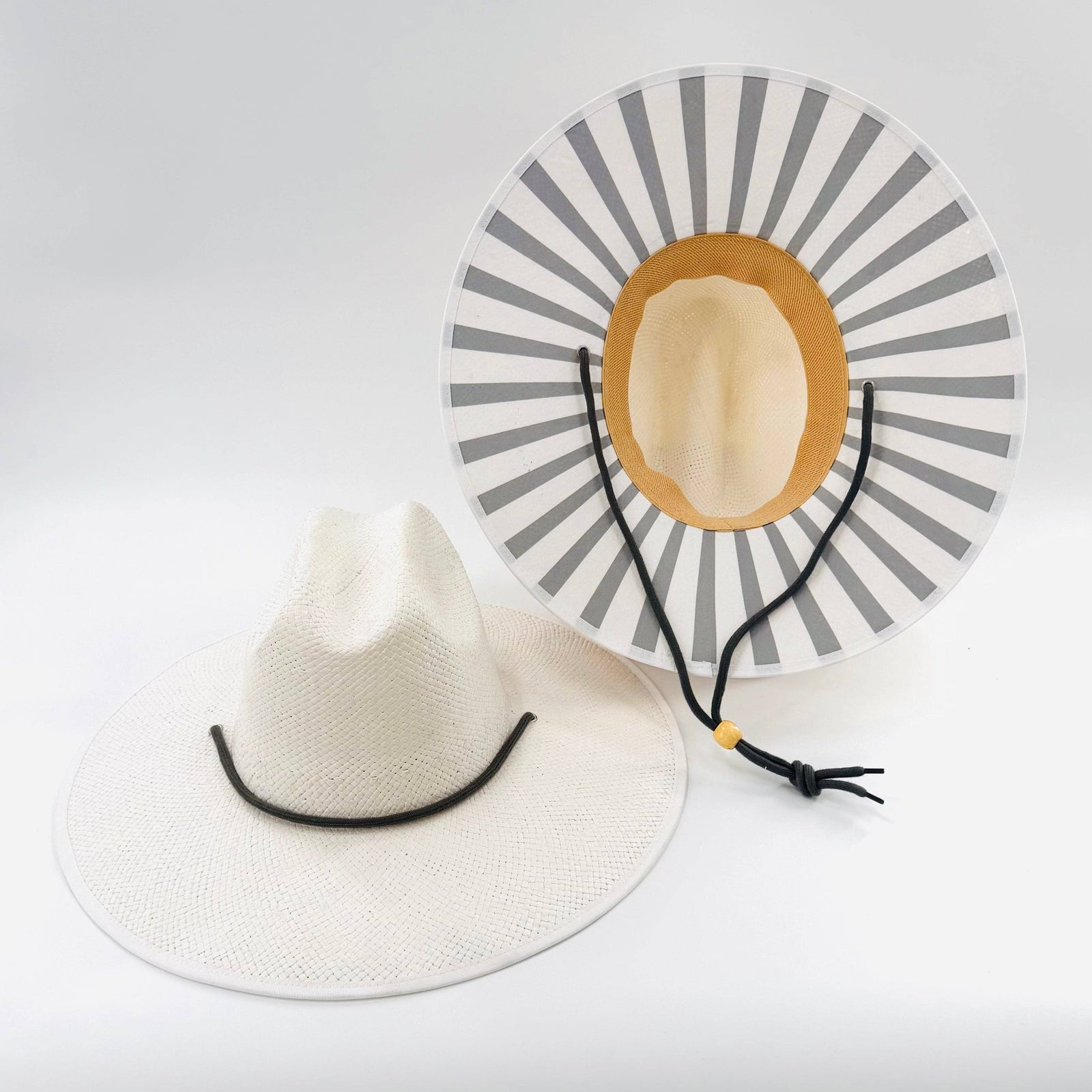 Two hats, one white and one with a gray and yellow design, on a light gray background.