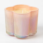 Iridescent glass candle holder with a lit candle on a white background