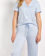 Woman wearing light blue short sleeve button down pajama top and matching drawstring pants