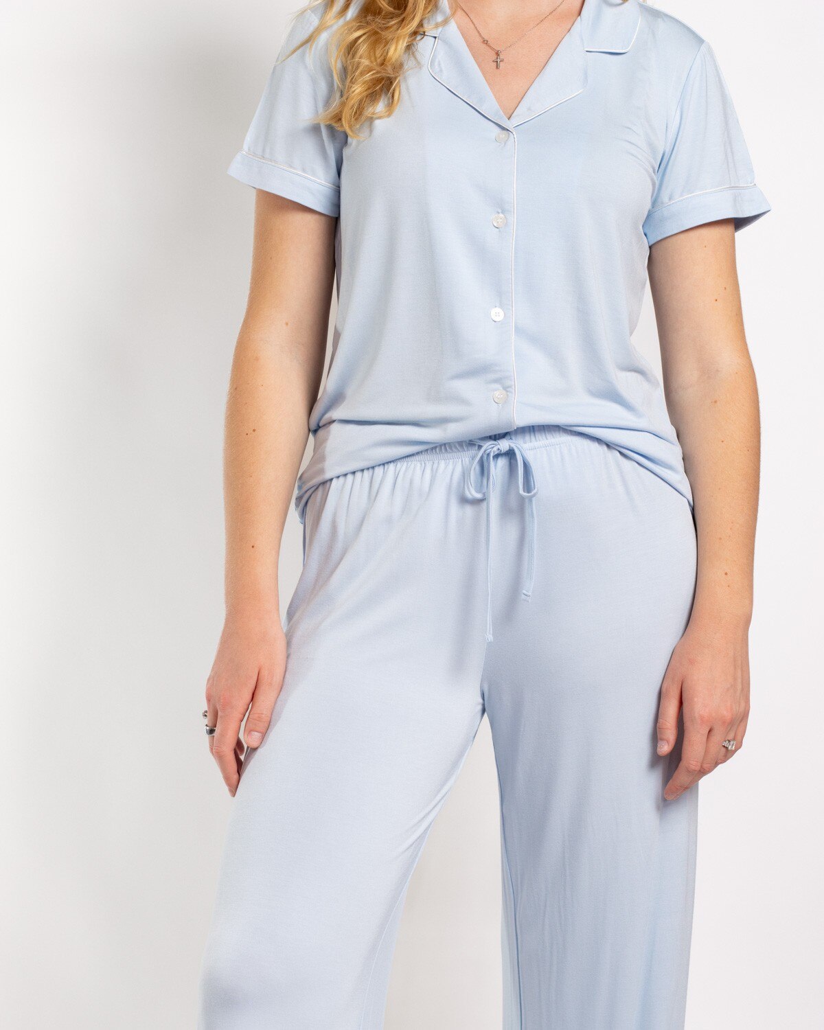 Woman wearing light blue short sleeve button down pajama top and matching drawstring pants