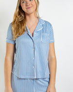 Woman wearing a blue and white vertical striped short sleeve button down pajama top