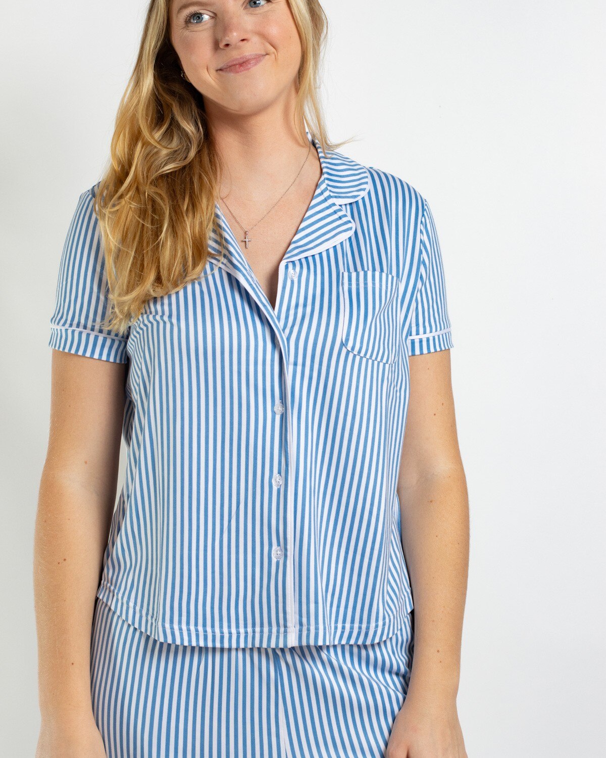 Woman wearing a blue and white vertical striped short sleeve button down pajama top