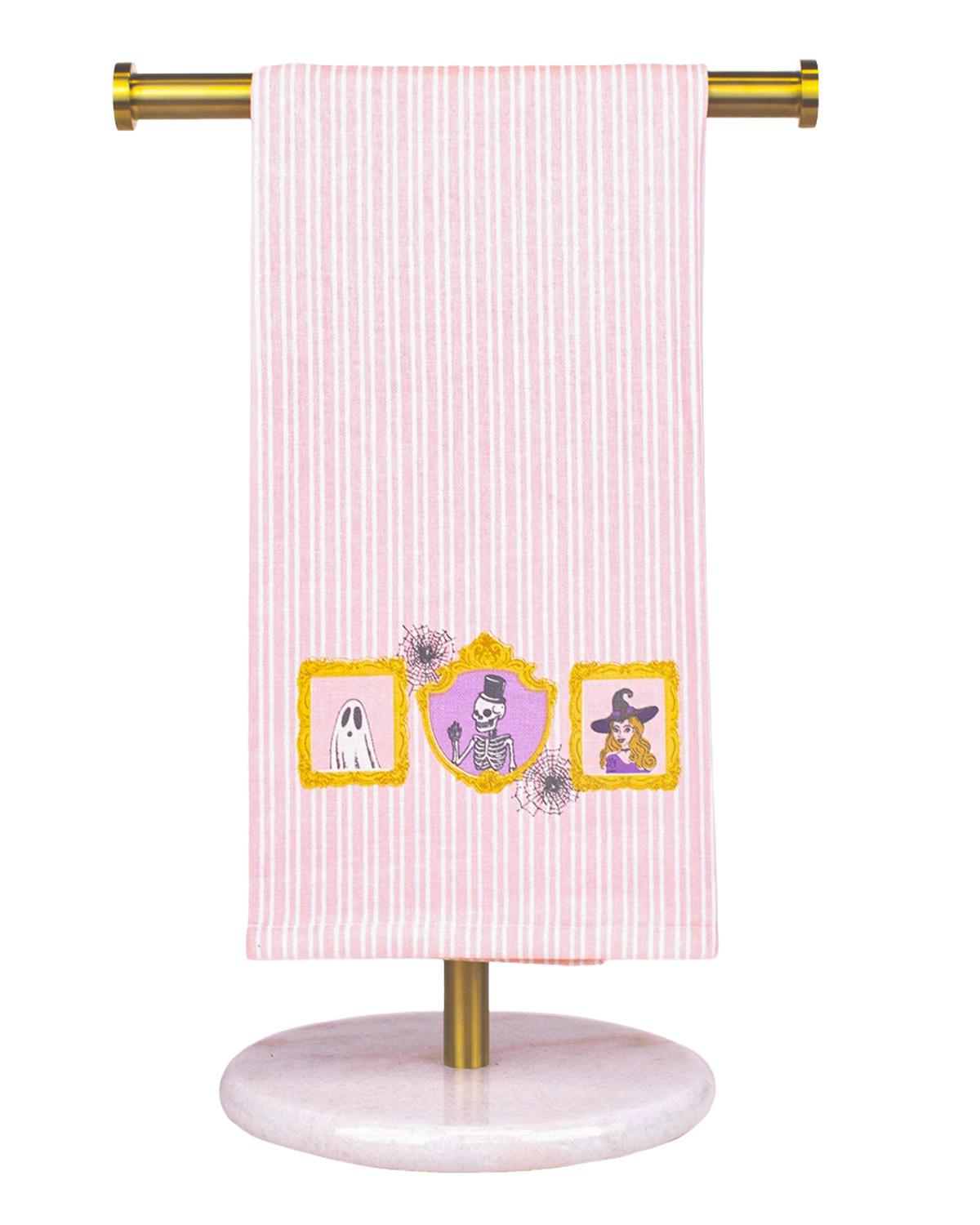 Pink striped hand towel with framed ghost and pumpkin portraits along the bottom