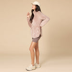 Woman wearing a beige fleece zip up jacket with a drawstring waist and a baseball cap