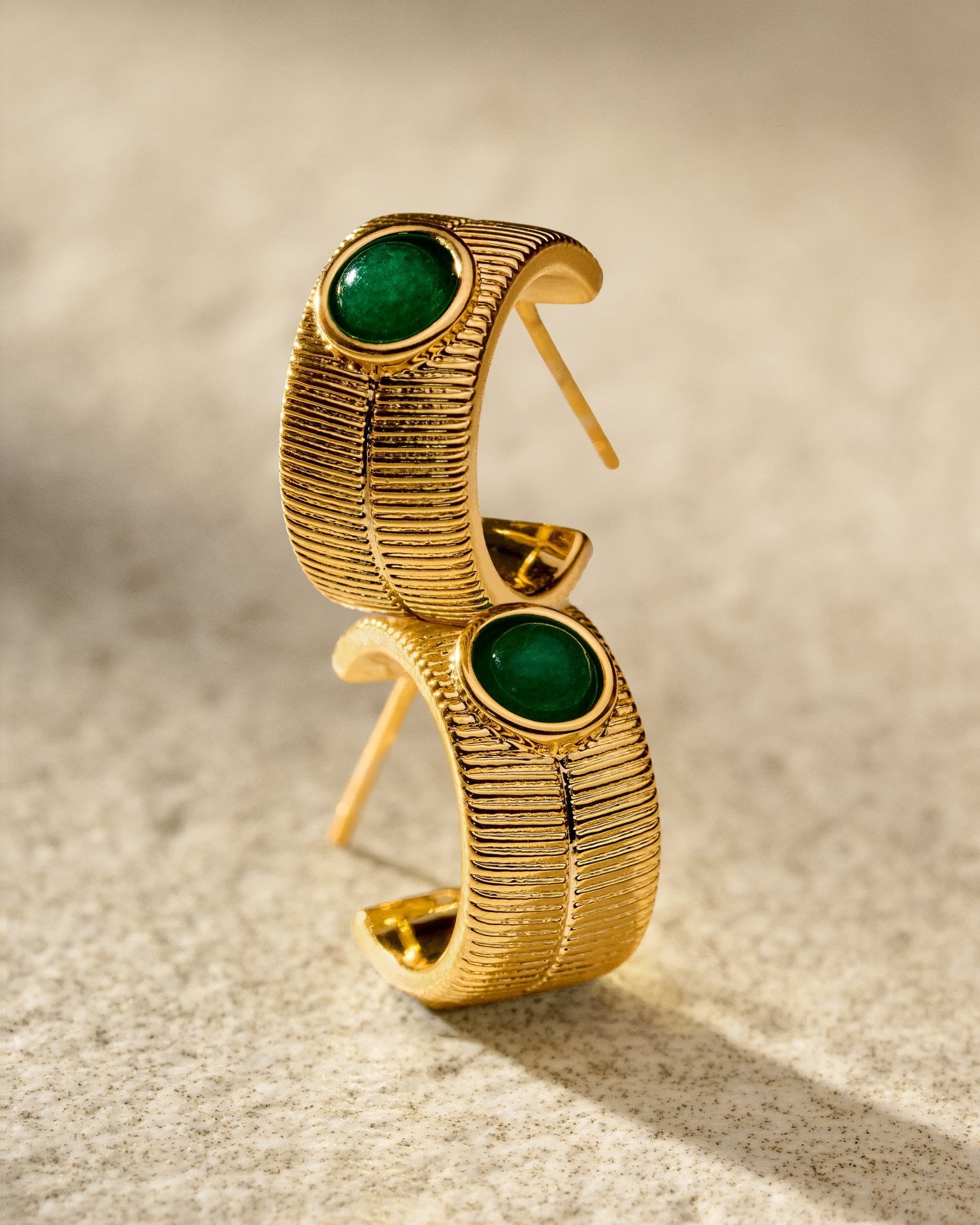 Gold hoop earrings with textured finish and round green stone inlay
