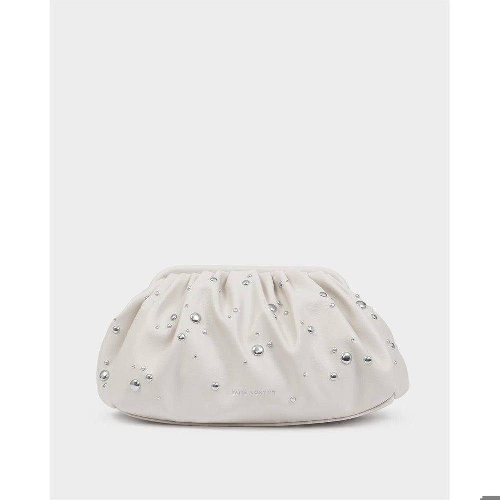 Vegan leather clutch bag by Katie Loxton presented in a studio setting, featuring an off-white ruched pouch silhouette embellished with scattered silver studs and the brand logo