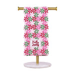 Hand towel with pink green and red geometric star pattern and Holly Jolly text on a gold stand
