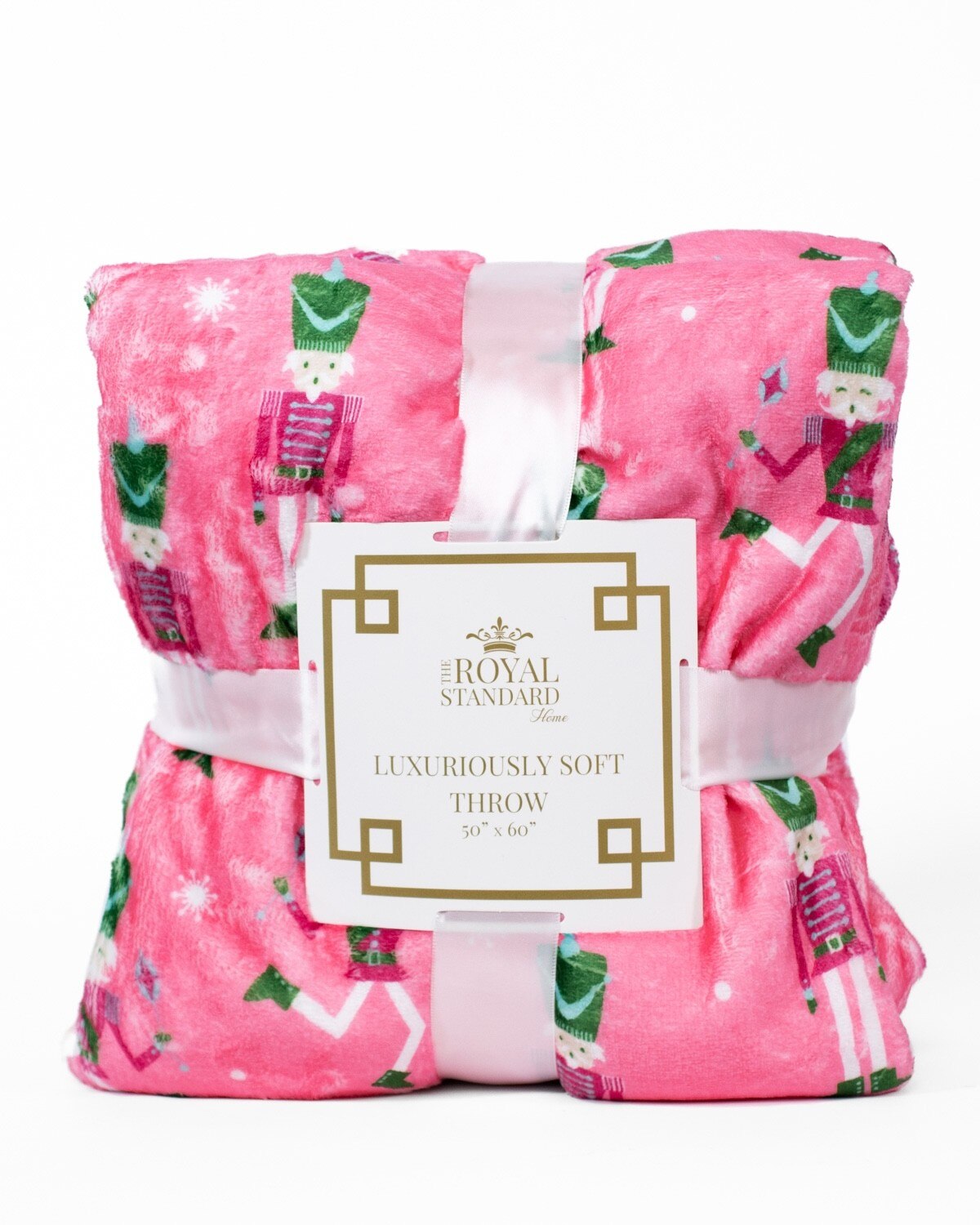Pink throw blanket with nutcracker pattern and The Royal Standard Home product label