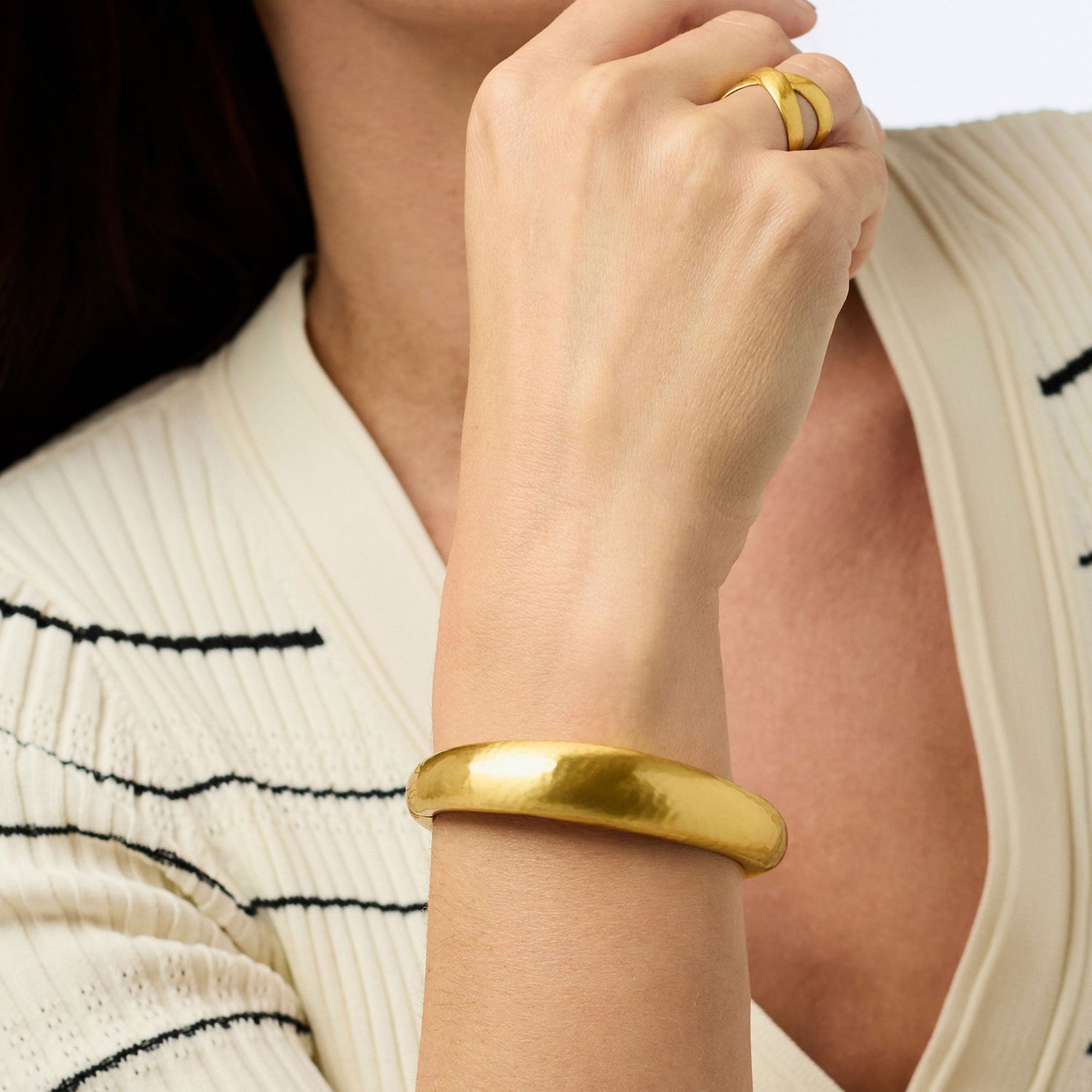 Gold bangle bracelet and gold crossover ring worn on a wrist