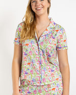 Woman wearing light green short sleeve button down pajama top with mahjong tile print
