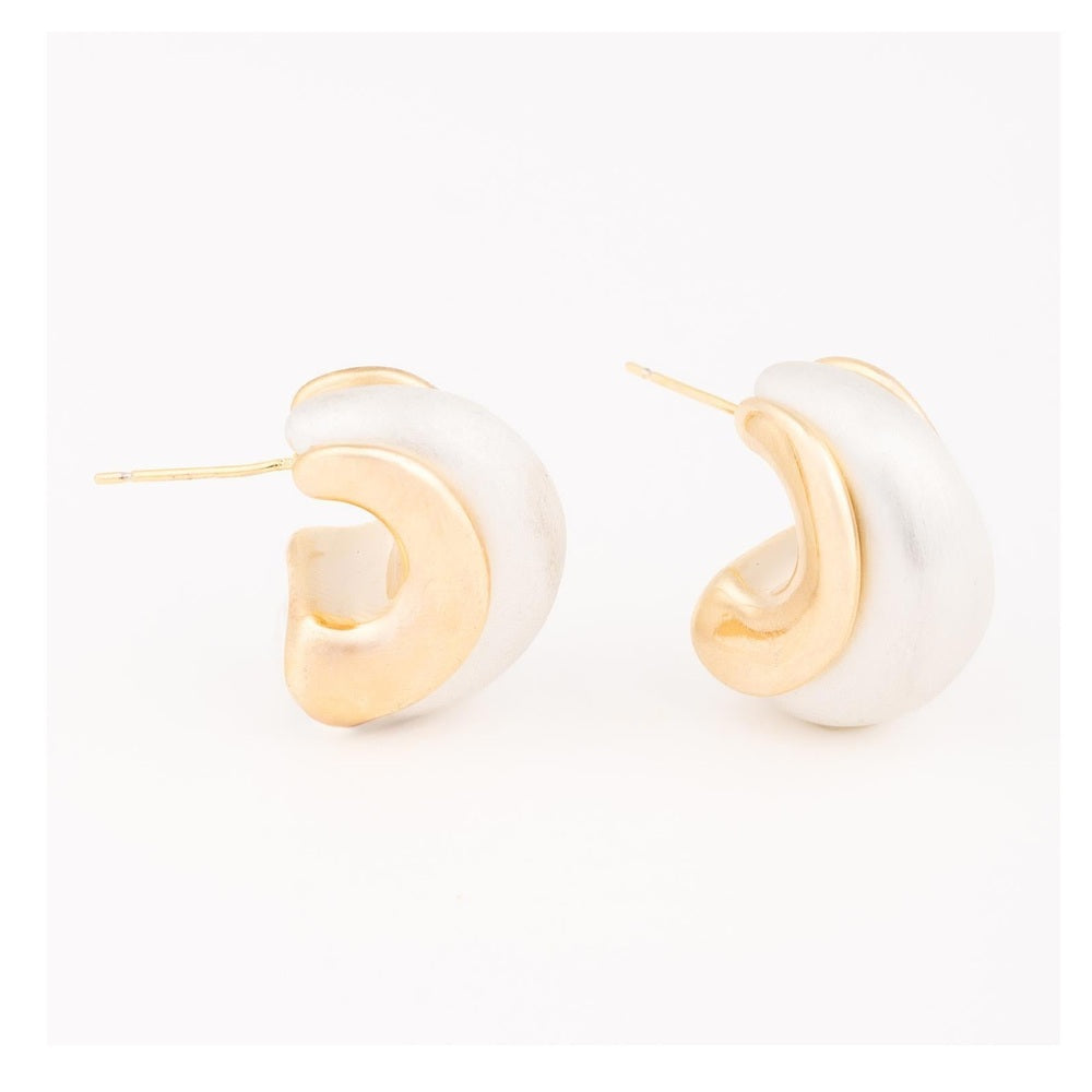 Gold and silver jewelry pair of sculptural C-shaped stud earrings displayed on a white studio background featuring a polished gold-tone inlay nestled against a larger matte frosted silver-tone curve with thin straight posts