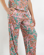 Person wearing pink floral print pajama pants with green leaves and orange flowers