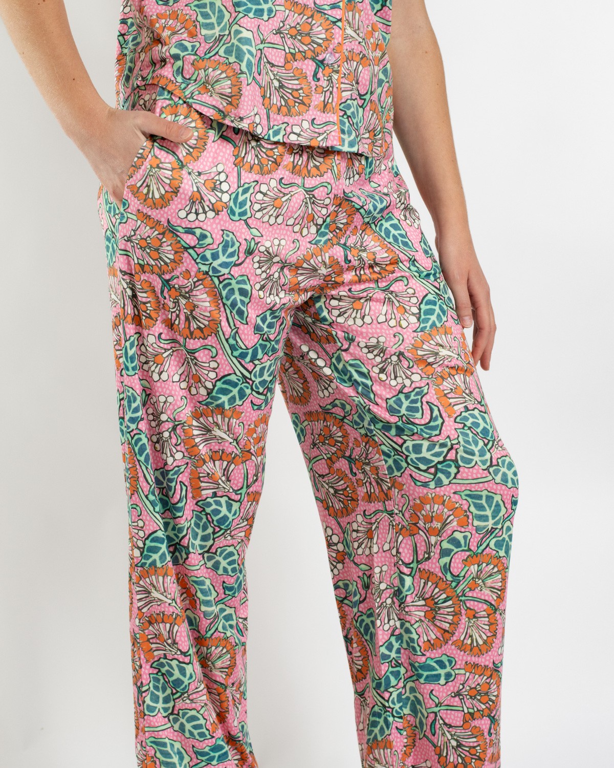 Person wearing pink floral print pajama pants with green leaves and orange flowers