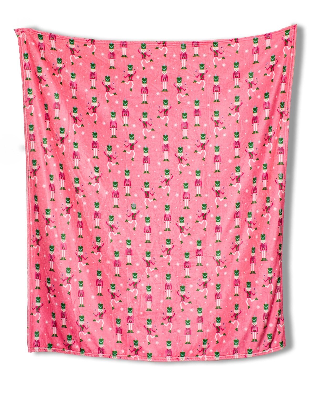 Pink blanket with a repeating pattern of nutcracker soldiers and white snowflakes