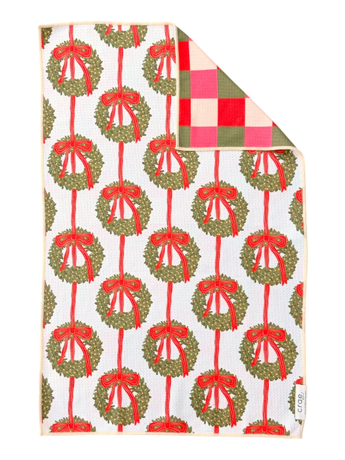 Hand towel printed with green wreaths on red ribbons, corner folded to show pink, red and green checks