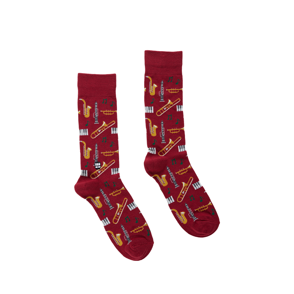 Pair of red crew socks featuring a repeating pattern of musical instruments and piano keys