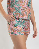 Woman wearing pink floral print pajama shorts with orange piping and side pockets