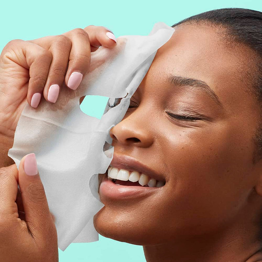 Person applying a white sheet mask to their face