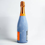 Bottle of champagne with a blue label and gold foil cap on a white background