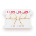 Gold beaded bow necklace on a 'Beaded Blondes' branded card.