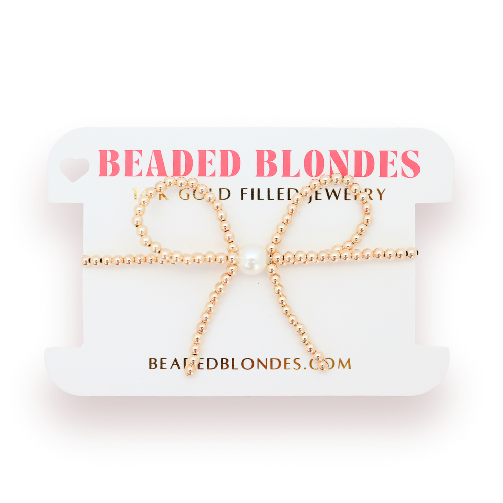 Gold beaded bow necklace on a 'Beaded Blondes' branded card.