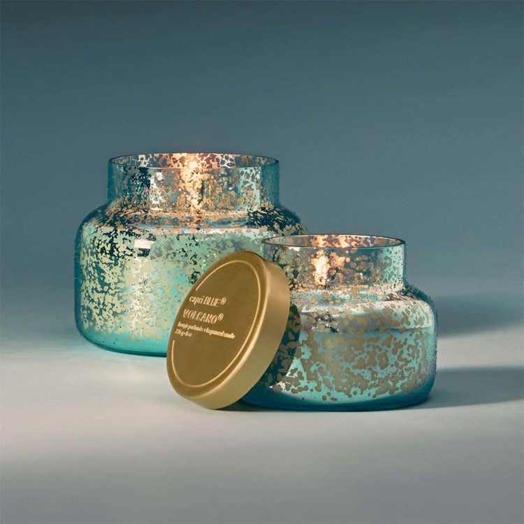 Two turquoise mercury glass candle jars with gold lids on a gray background