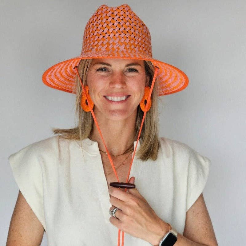 Woman wearing an orange woven hat with matching chin strap against a plain background