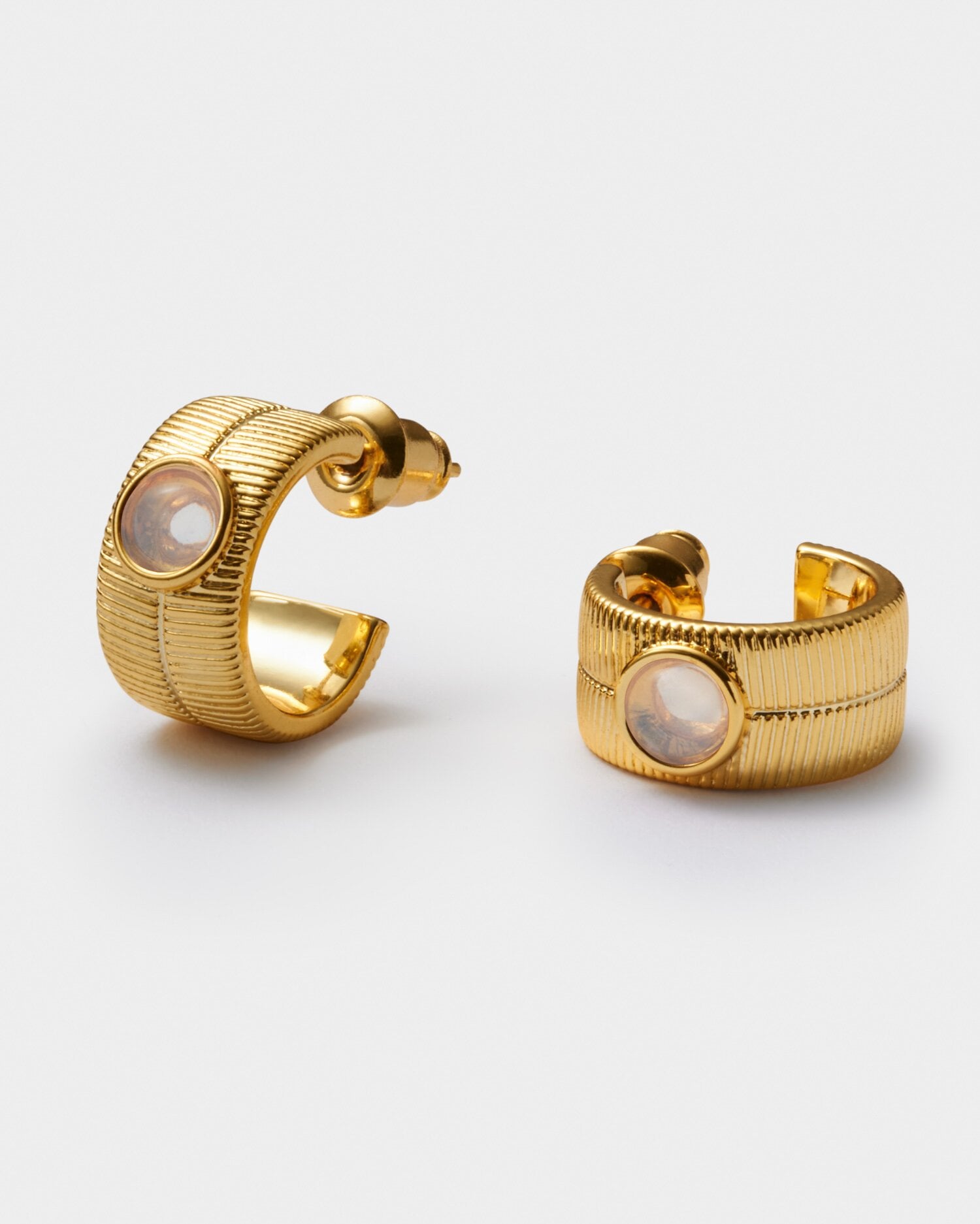 Gold hoop earrings with textured ribbed detail and a central round stone