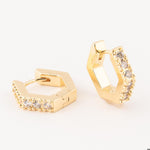 Gold-toned jewelry featuring a pair of geometric hexagonal huggie earrings with a row of sparkling clear round-cut stones and a polished finish displayed on a white studio background