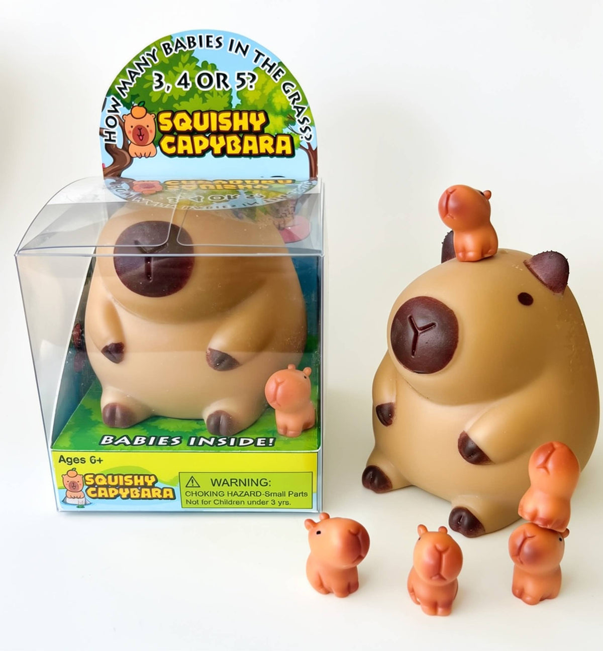 Squishy Capybara toy box beside a large capybara with tiny baby capybaras around and on top of it
