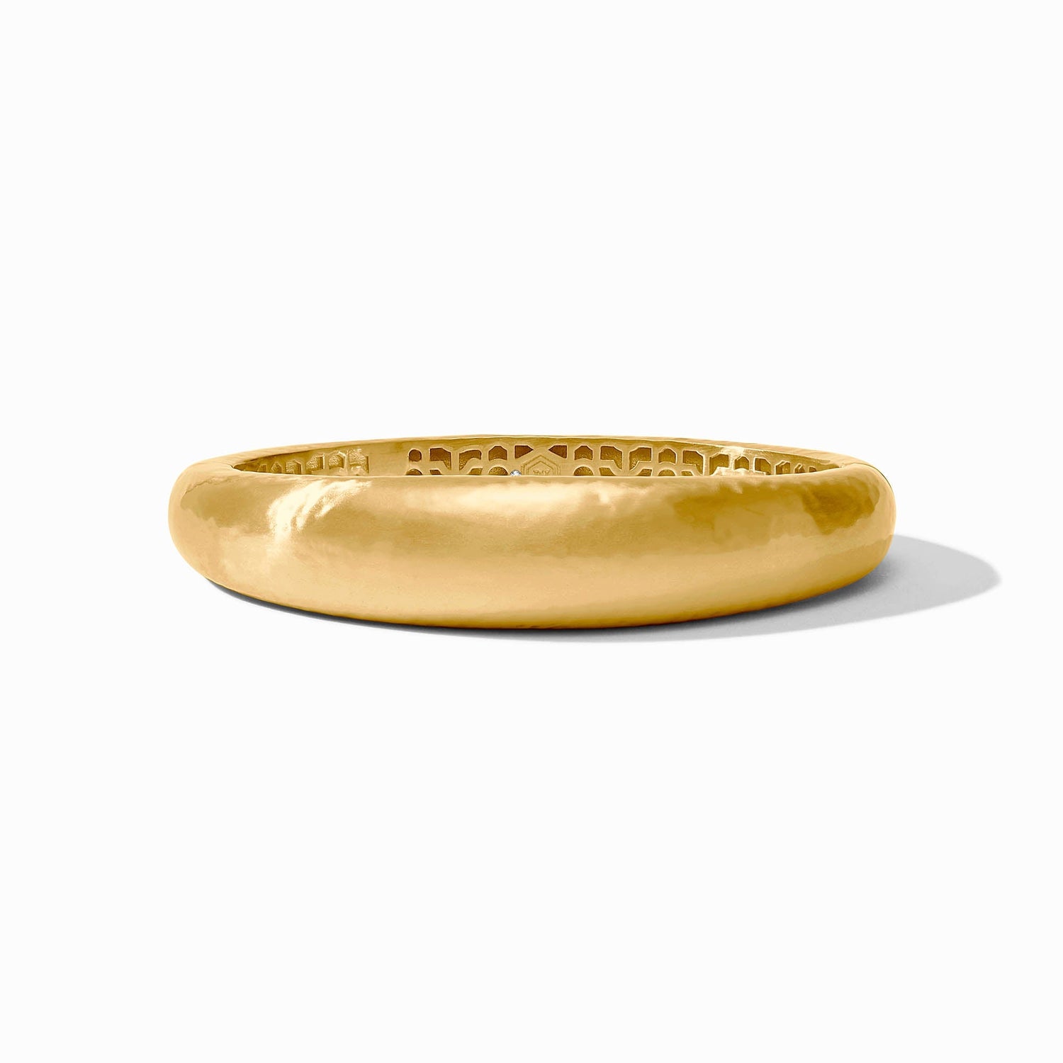 Gold bangle bracelet with a smooth outer surface and intricate cutout pattern on the inner band