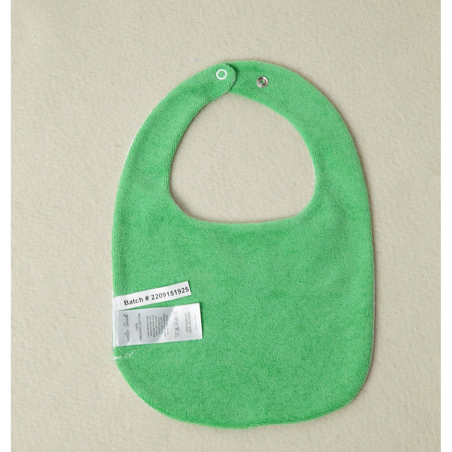 Green baby bib with a label on a beige background