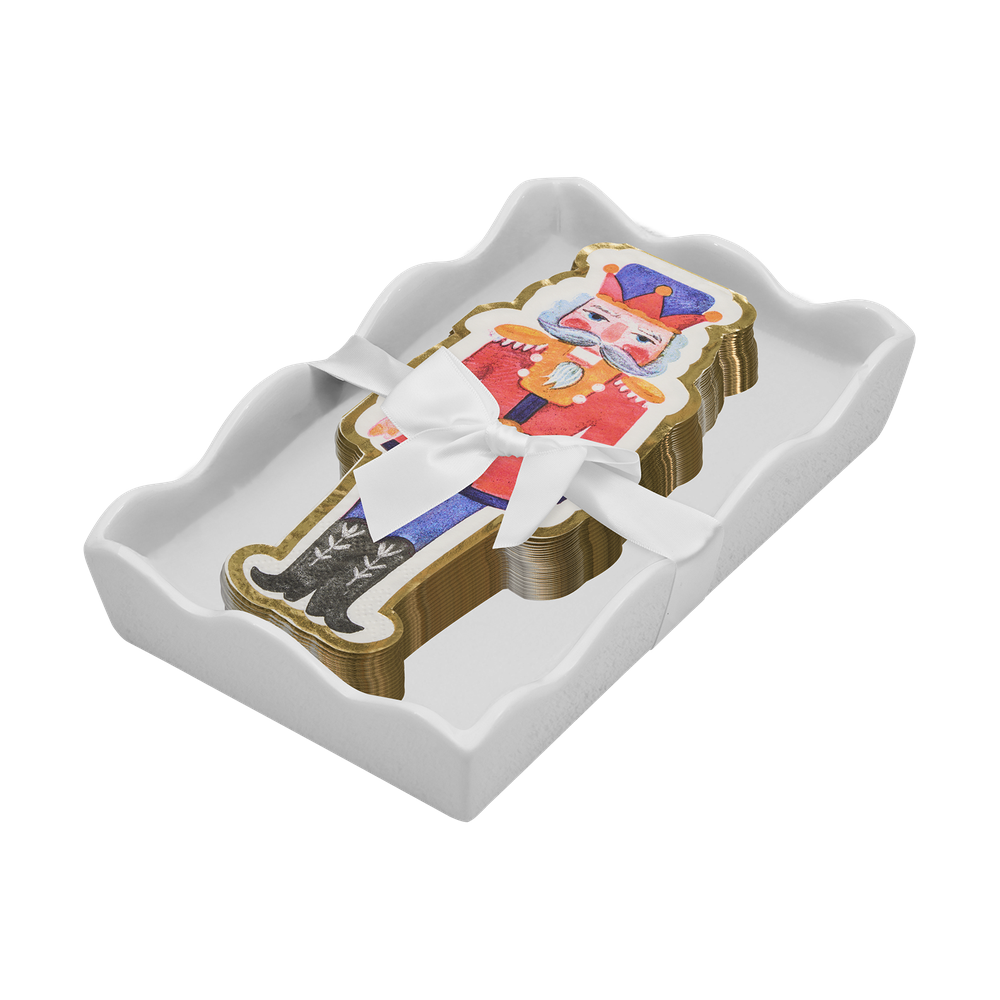 Stack of nutcracker shaped paper napkins tied with a white ribbon in a white scalloped tray